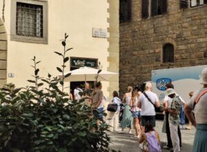 People queue outside Vivoli beneath its green sign on Florence's Via dell'Isola delle Stinche, beside a stone facade.