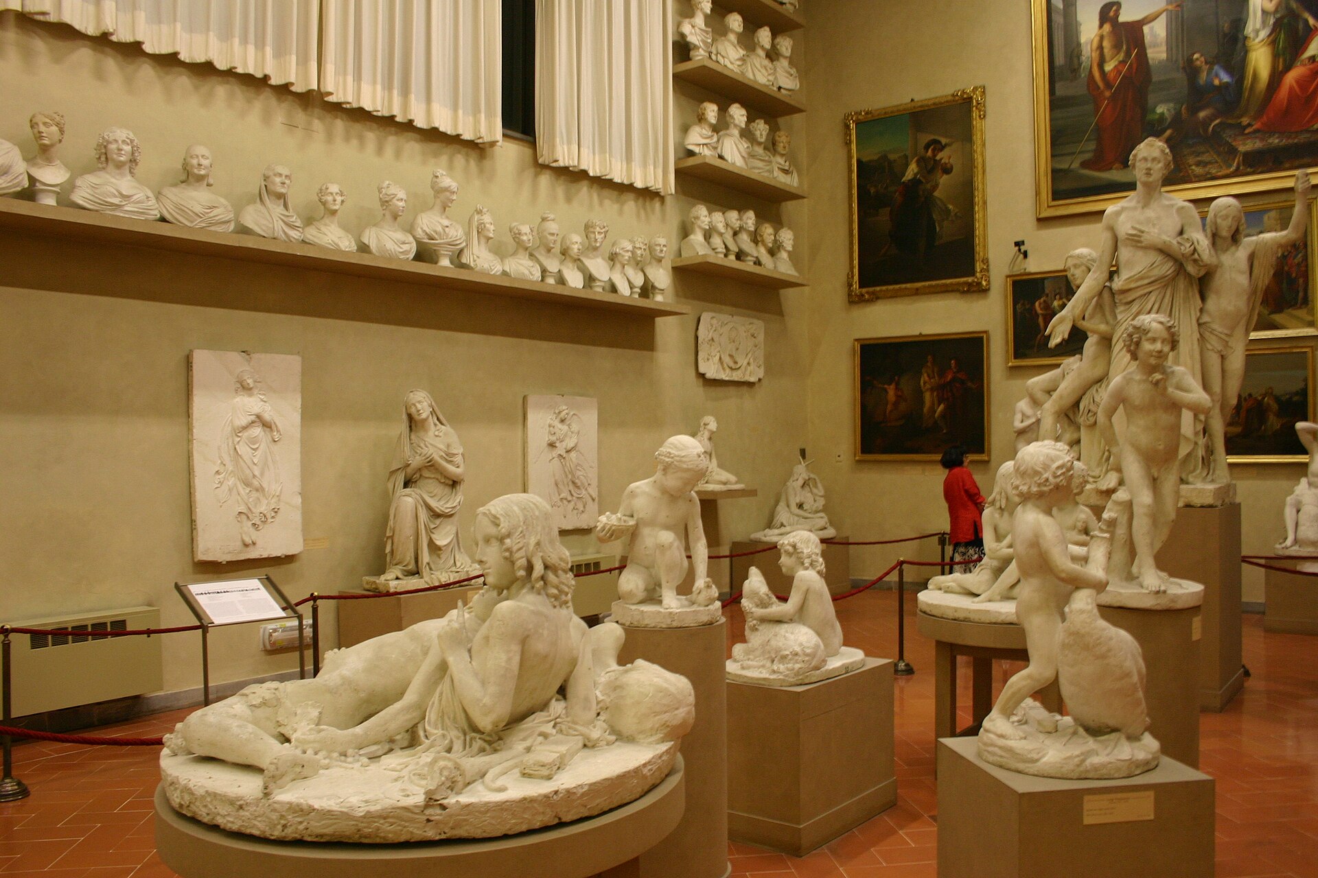 Plaster statues and portrait busts fill the Gipsoteca Bartolini at Florence's Accademia, with paintings above the displays.