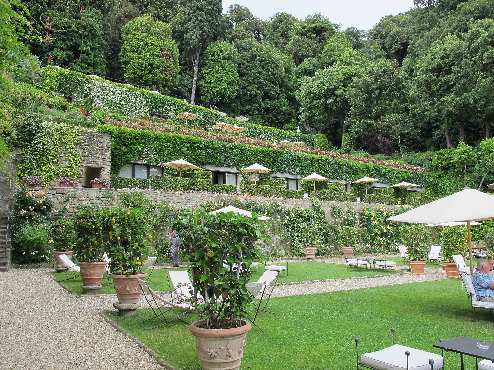 Potted citrus trees and garden chairs line the lawns beneath ivy-covered terraces at Villa San Michele in Fiesole.