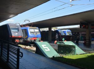 Regional trains stand at the buffer stops of Florence Santa Maria Novella, under concrete canopies and overhead wires.