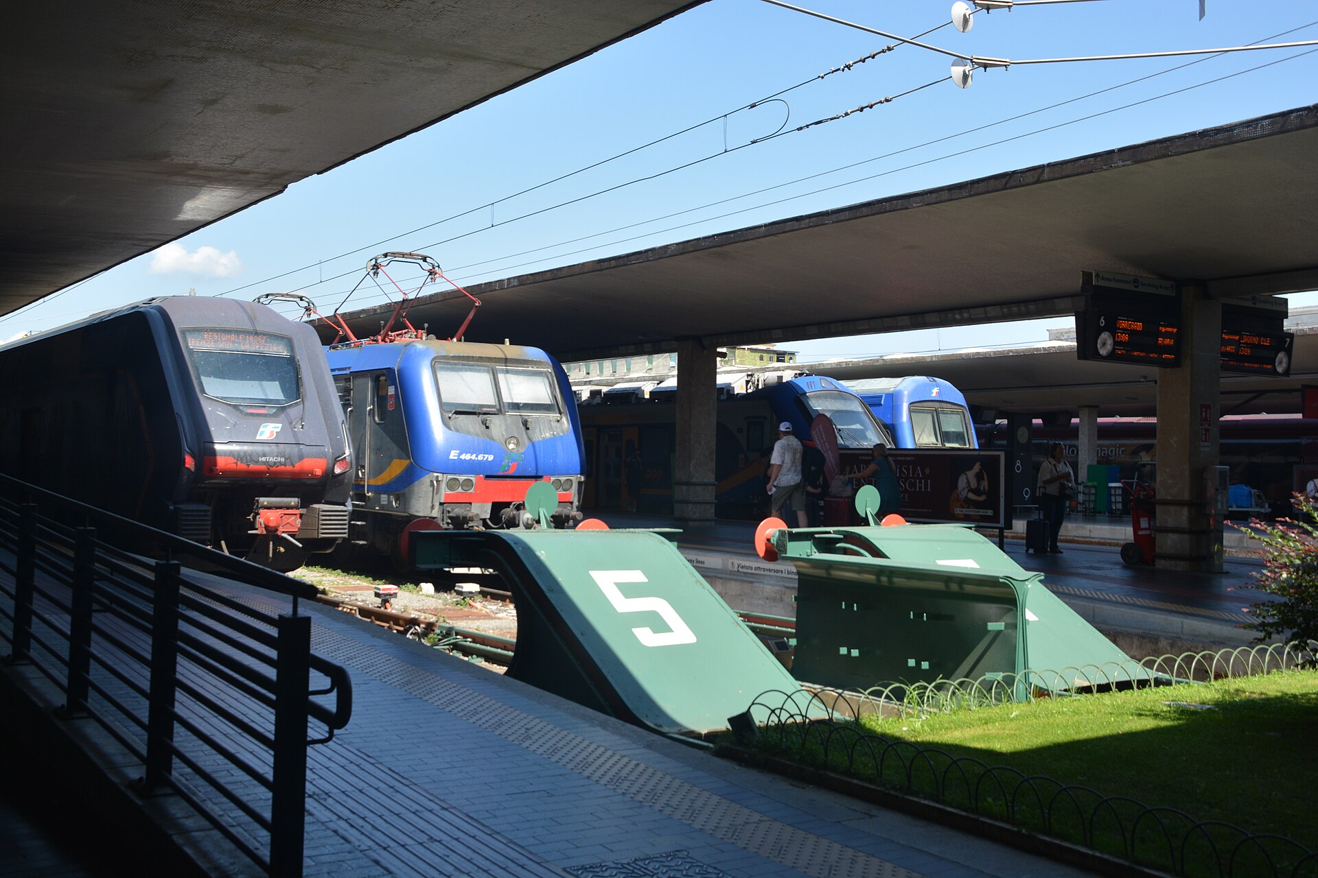 Regional trains stand at the buffer stops of Florence Santa Maria Novella, under concrete canopies and overhead wires.