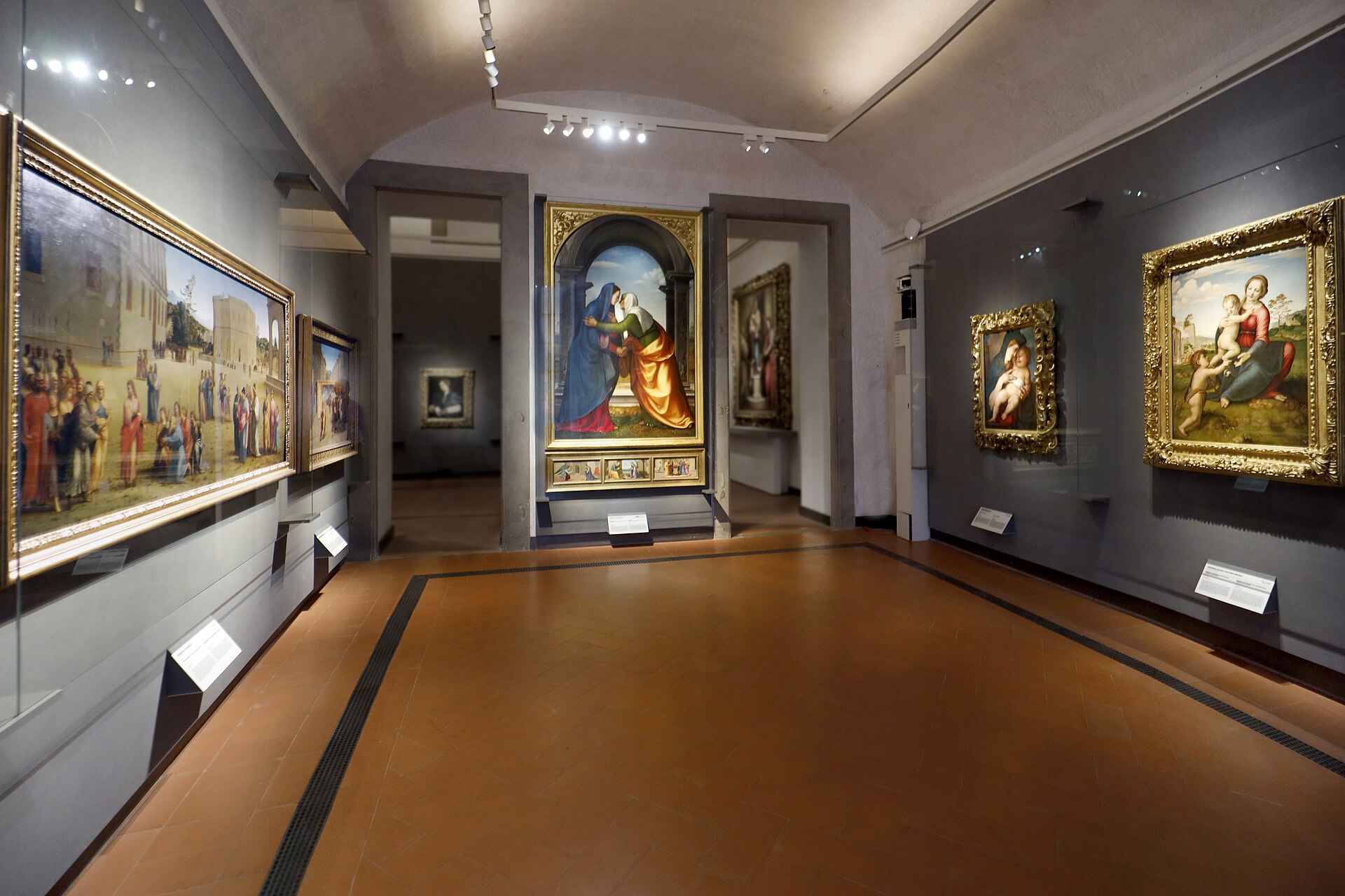 Renaissance paintings in gilded frames surround the terracotta floor of the Granacci and Berruguete room at Florence's Uffizi Gallery.
