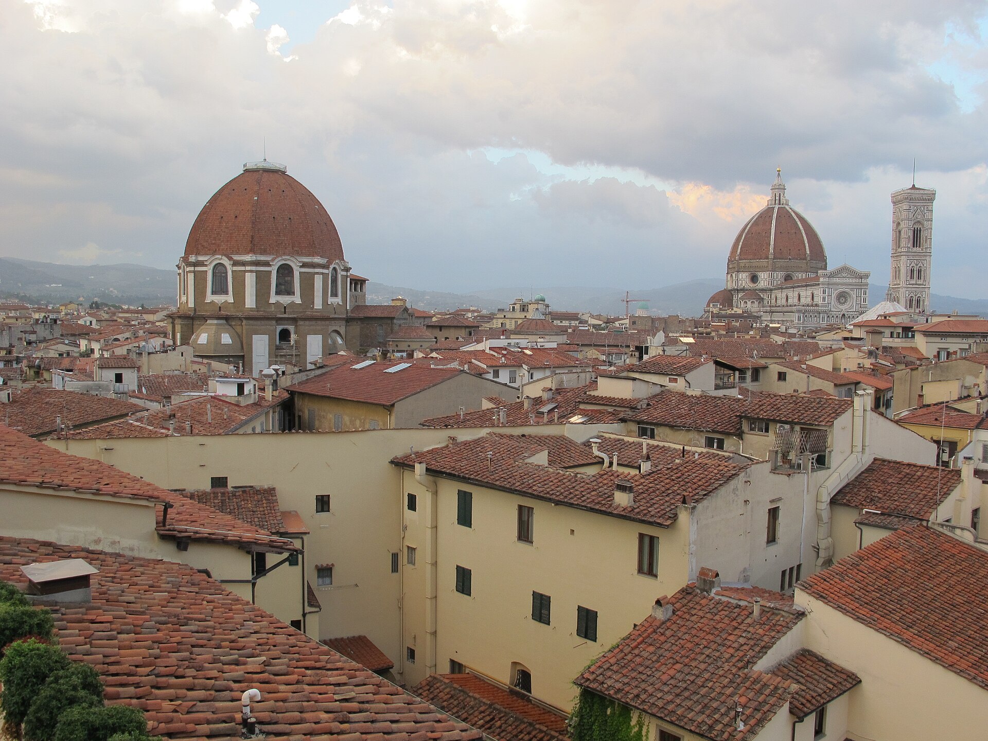Rooftop view over central Florence at dusk with the San Lorenzo dome at left and the Duomo and bell tower on the right skyline