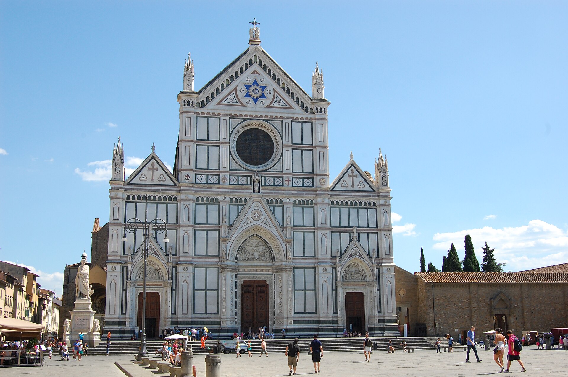 Santa Croce in Florence displays its patterned marble facade, pointed portals and rose window above visitors in the piazza.