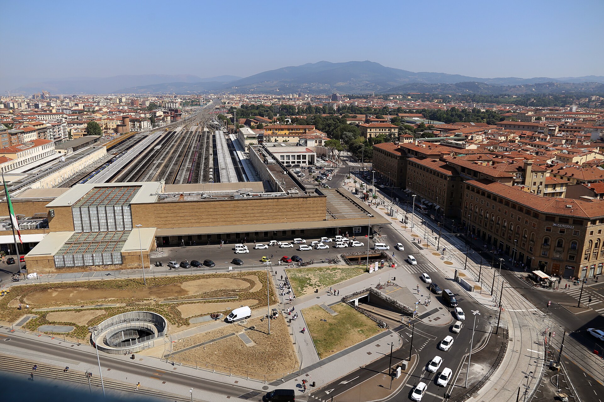 Santa Maria Novella station in Florence stretches behind a forecourt lined with white taxis and pedestrians.