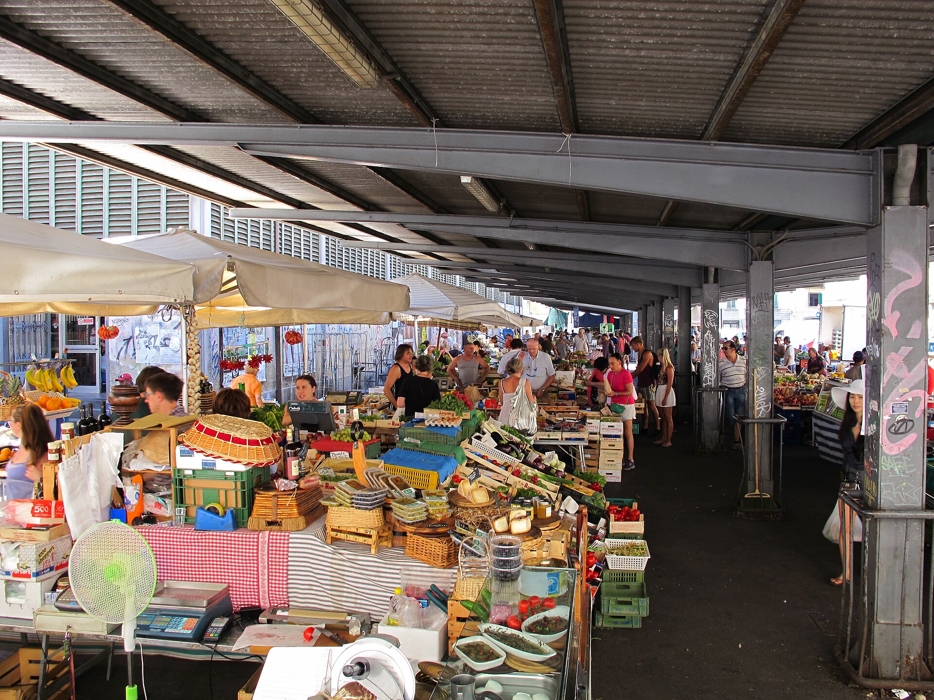Shoppers browse cheeses, jars, eggs and produce beneath the covered arcade of Florence's Sant'Ambrogio market.
