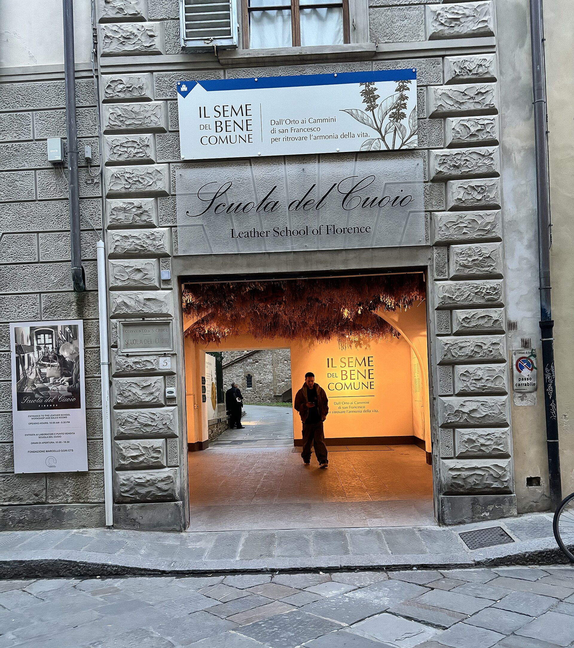 The signed stone entrance to Scuola del Cuoio in Florence opens onto a warmly lit passage and courtyard.