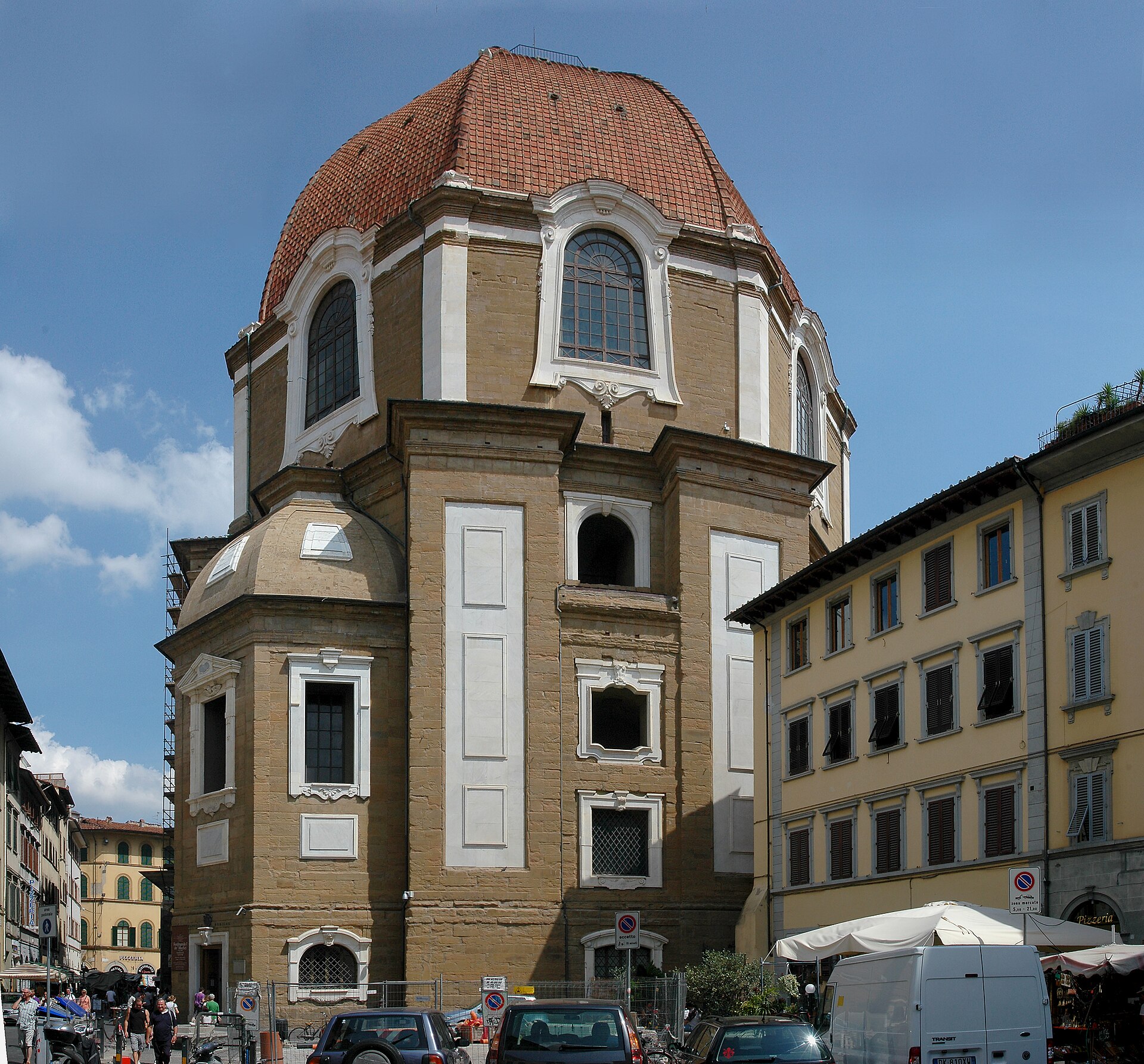 The tiled dome and octagonal walls of the Princes' Chapel rise above street stalls beside San Lorenzo in Florence.