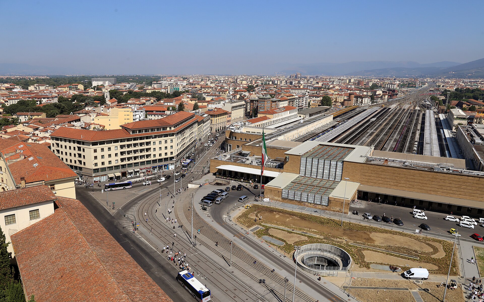 Tram tracks curve past Florence Santa Maria Novella station, seen above its entrance glazing and stone frontage.