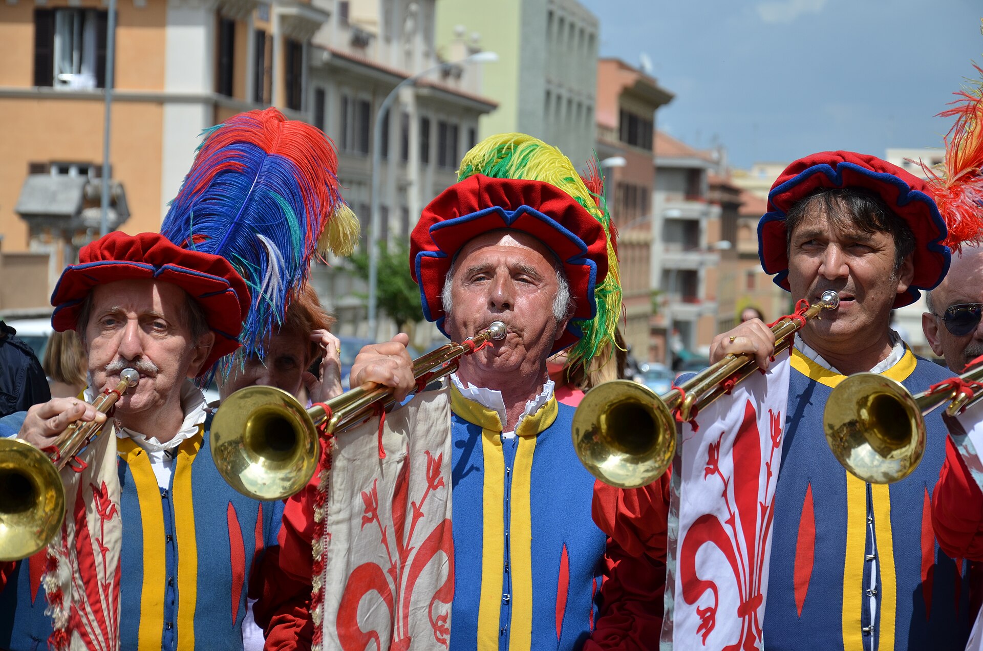 Trumpeters in bright Renaissance costumes and feathered caps play brass instruments during Florence's historical procession.