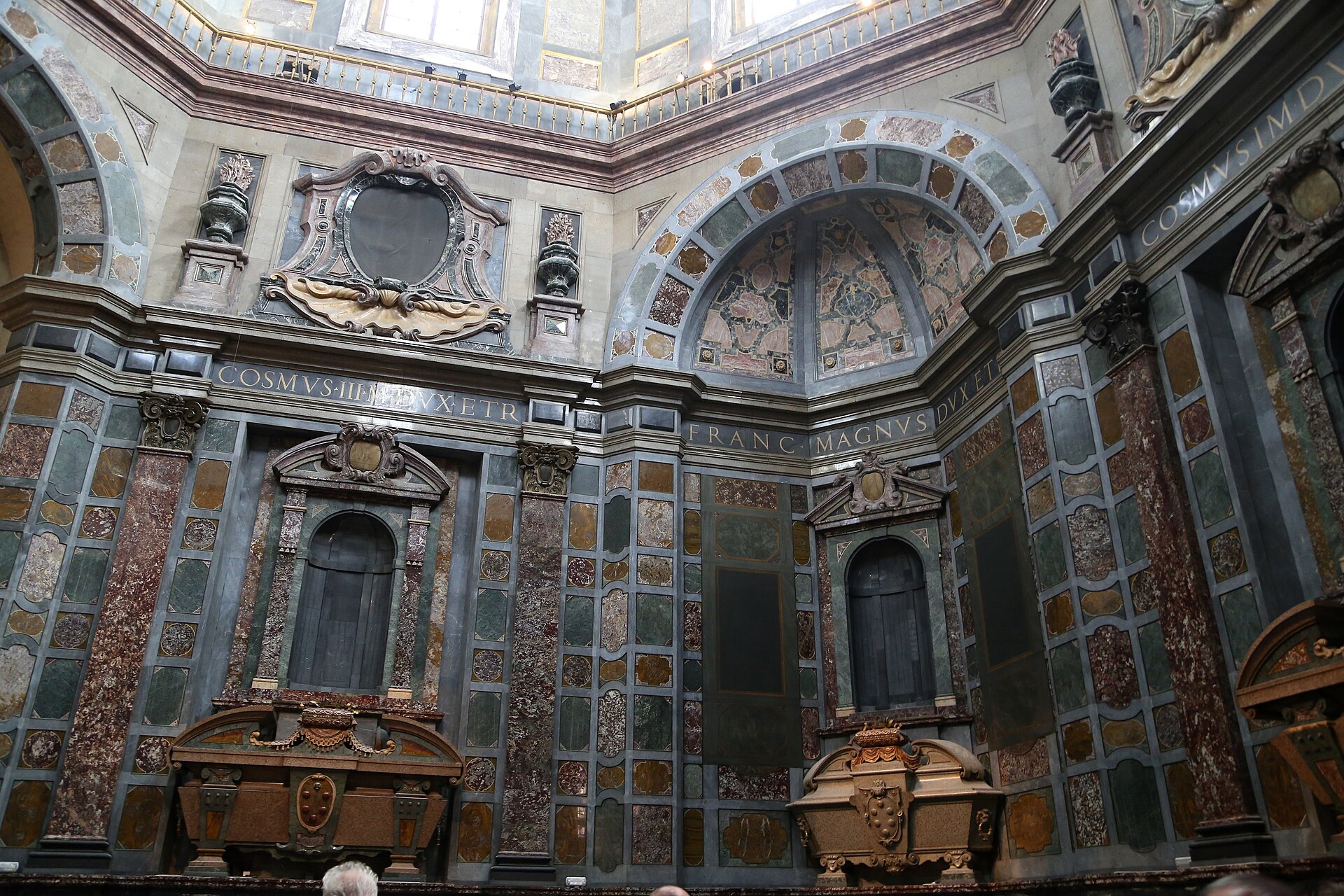 Two sarcophagi stand beneath tall niches amid the coloured stone walls of Florence's Princes' Chapel.