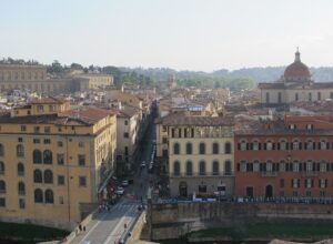 Via Maggio extends into Florence’s Oltrarno beyond Ponte Santa Trinita, surrounded by tiled rooftops and Santo Spirito’s dome.