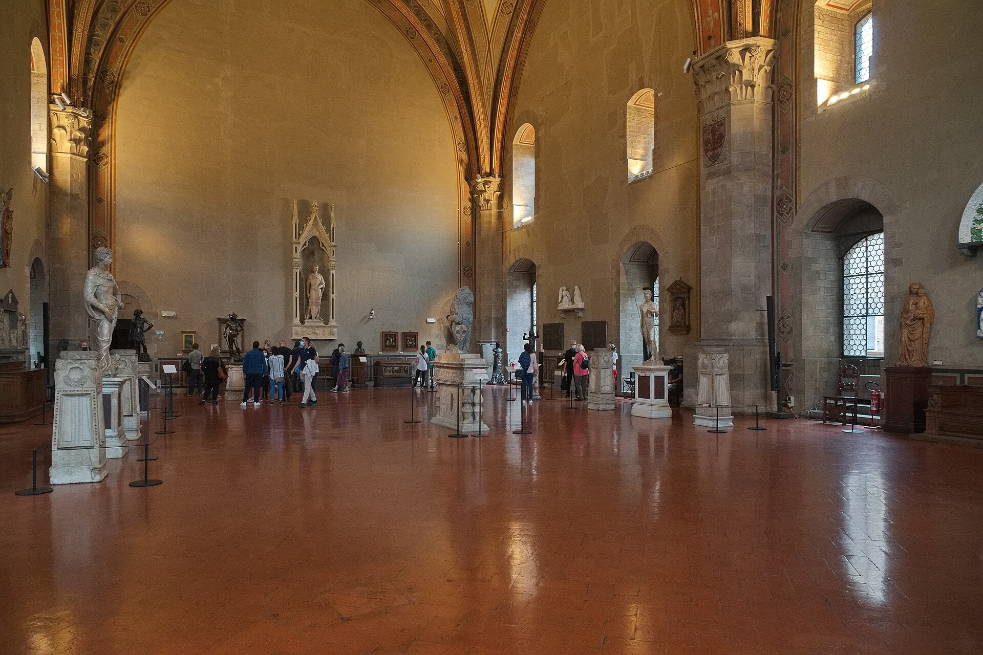 Visitors explore sculptures beneath the high vaults of the Donatello hall at Florence's Museo Nazionale del Bargello.