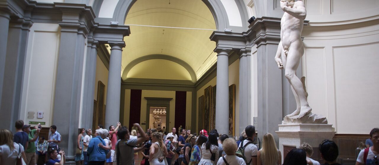 Visitors gather around Michelangelo's marble David beneath the arches of the Accademia Tribune in Florence.