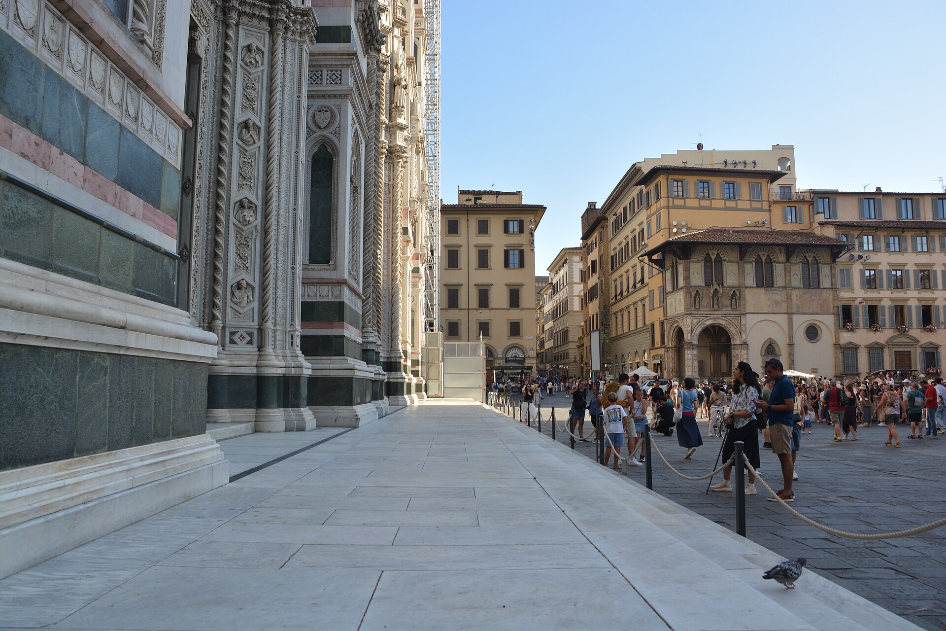 Visitors gather beside Florence Cathedral’s marble facade on Piazza del Duomo, with the square’s historic buildings beyond.