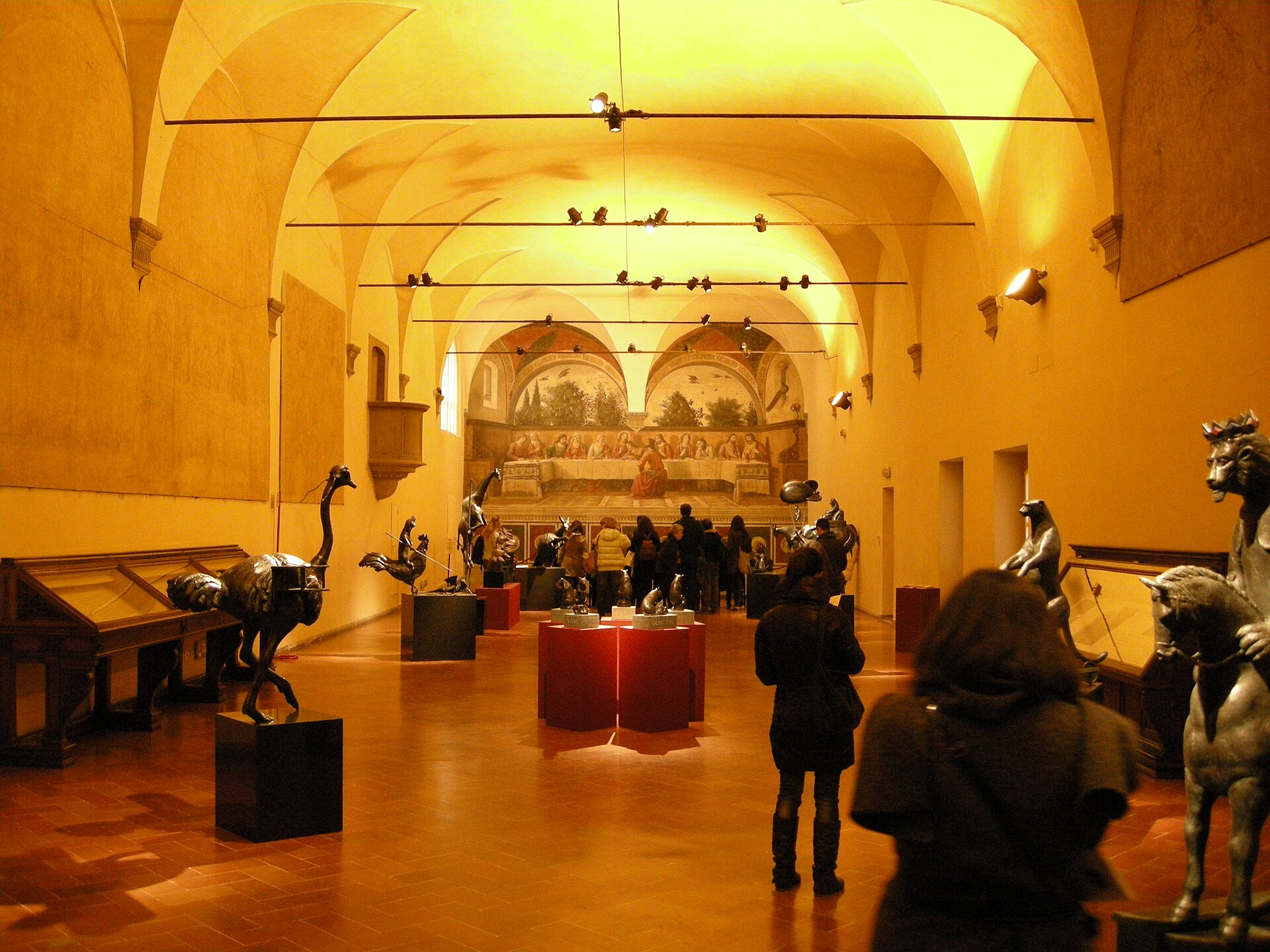 Visitors and sculpture displays fill Ognissanti's vaulted refectory in Florence, with Ghirlandaio's Last Supper fresco on the far wall.