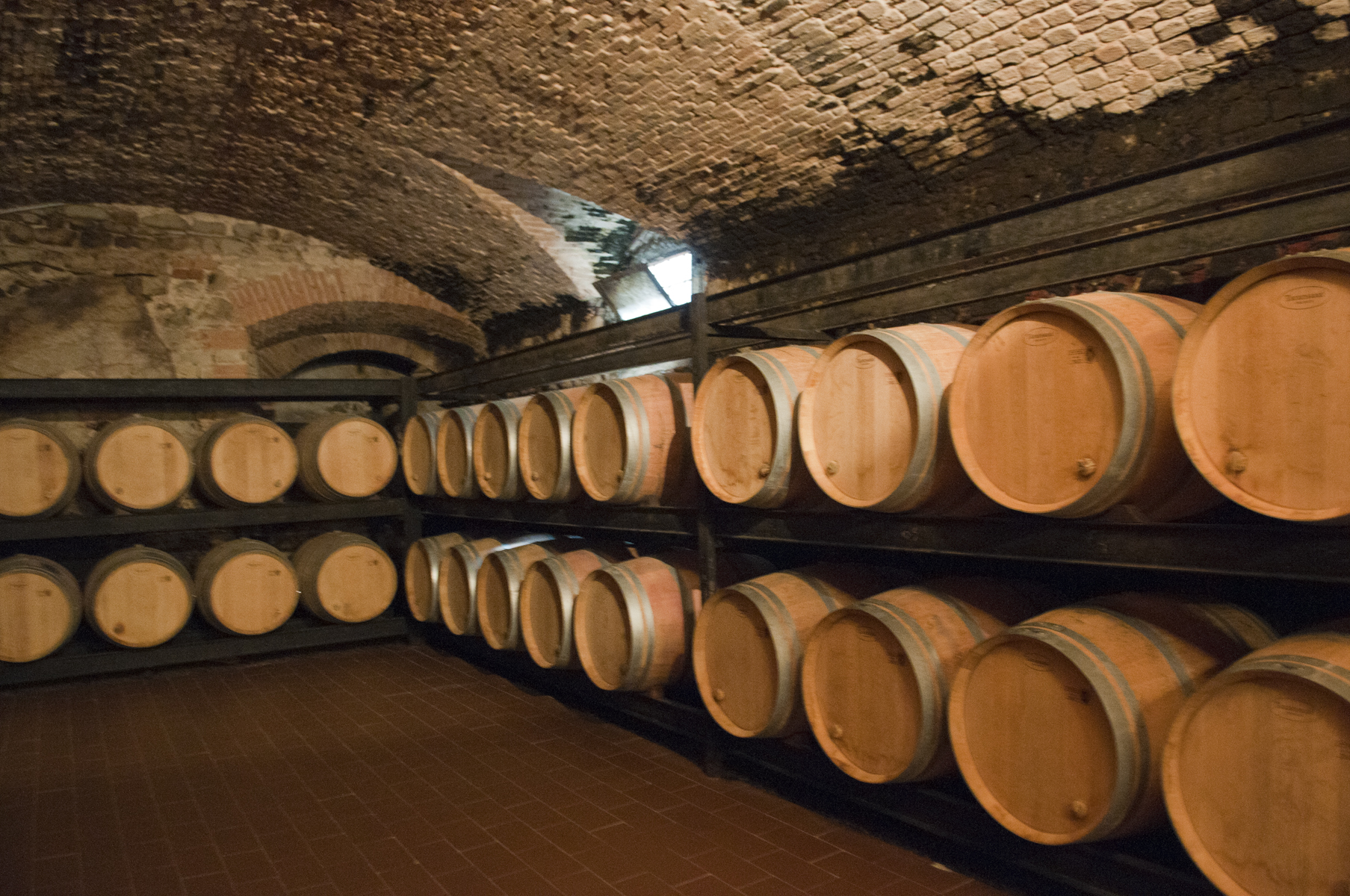Wooden barrels rest on two tiers of racks beneath the vaulted brick ceiling of Vignamaggio’s cellar in Chianti.